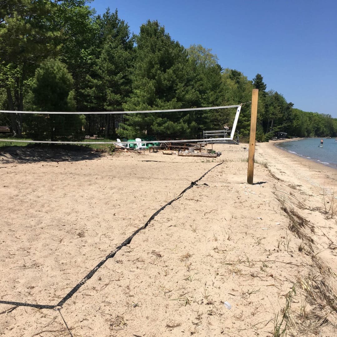 A volleyball net on the beach near water.
