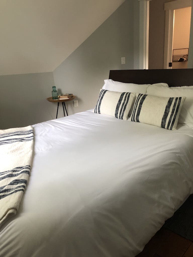 A bed with white sheets and pillows on it.
